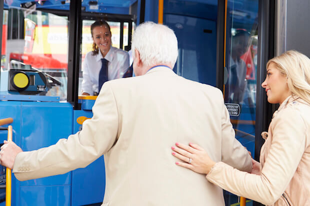 Woman Helping Senior Man To Board Bus