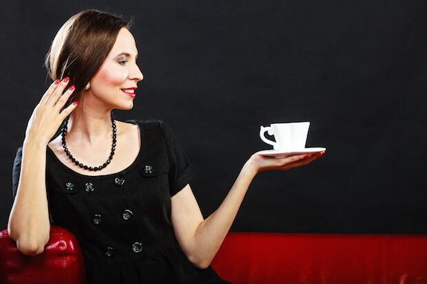 Retro woman holds tea cup sitting on sofa