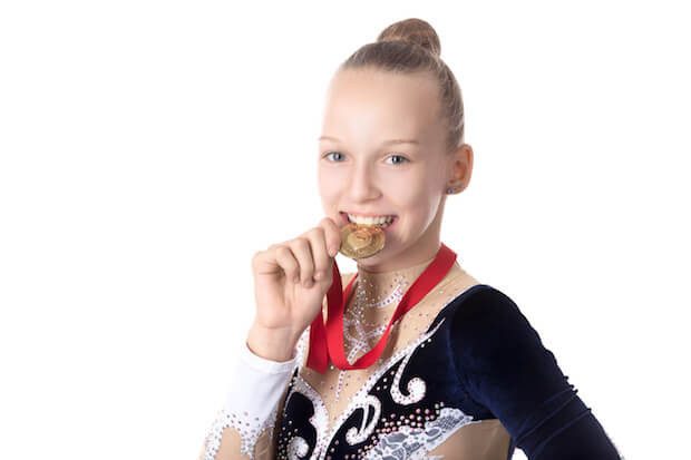 Gymnast girl biting her award medal